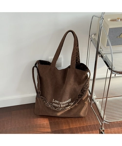 Detalle de bolso tote de pana con correas de leopardo e impresión de texto motivador