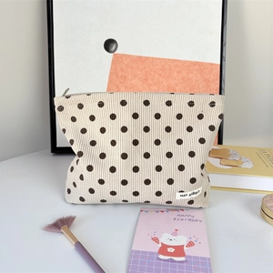 Detail of corduroy polka dot makeup bag with brand label and soft fabric texture