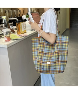 Vue latérale du grand sac cabas à carreaux en toile avec badge rond dans un café