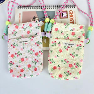 Close-up of floral fabric phone bags featuring MAY RABBIT label and woven shoulder strap
