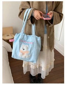 Detail of light blue polka dot drawstring bag featuring a cute white puppy embroidery