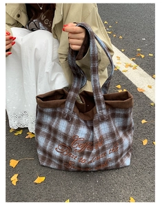 Close-up of plaid tote bag with coffee embroidery and corduroy details on autumn leaves