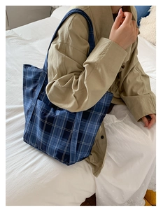Close-up of blue plaid nylon tote bag with front pocket shown on khaki trench coat