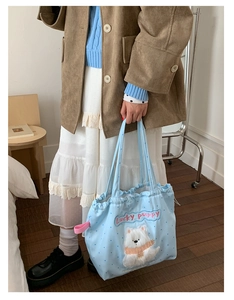 Detail of light blue polka dot tote bag featuring a plush puppy patch and drawstring