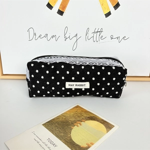 Close-up of black polka dot corduroy cosmetic bag with white lace trim and metal zipper
