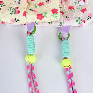 Detail of floral quilted crossbody bag with adjustable checkered straps and green metal rings