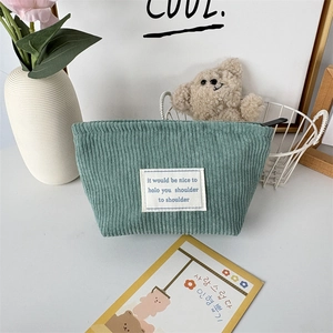 Detail view of bean green corduroy makeup bag with top zipper and white patch label