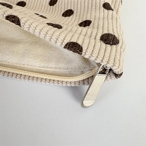 Detailed close-up of corduroy polka dot makeup bag with a silver metal zipper
