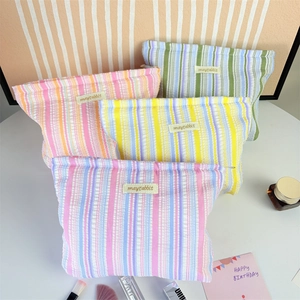 Detail of multi-color striped cosmetic bags featuring textured pleats and zip closure
