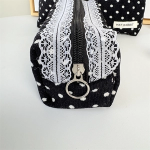 Detailed close-up of corduroy polka dot makeup bag with lace trim and metal ring zipper