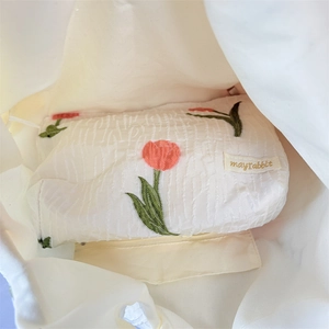 Detail der Tulpenstickerei auf cremefarbenem Faltenstoff und Innenraum des Beutels