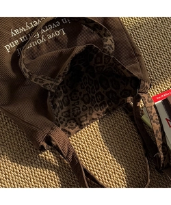 Detalle de bolso tote de pana marrón oscuro con forro de leopardo y bordado en blanco
