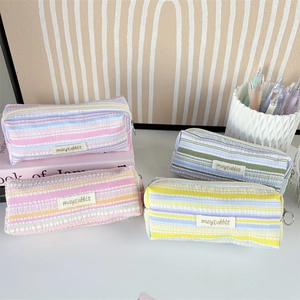 Macro detail of seersucker striped pencil cases with metal zippers and fabric texture