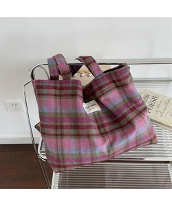 Detail of checkered tote bag with woven texture hanging on a minimalist metal stand