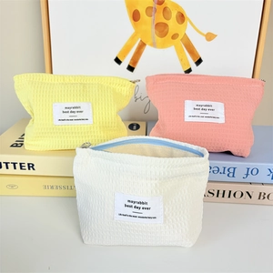 Detailed waffle texture on three small zippered cosmetic pouches in pastel colors