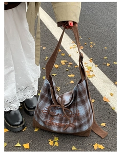 Detailed embroidery and bow on a plaid tote bag with corduroy trim in autumn light