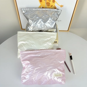 Quilted cosmetic bags in silver, pearl white and pink with embossed bow patterns