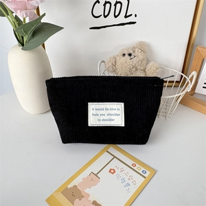 Macro detail of black corduroy makeup bag texture with zip and stylish woven label