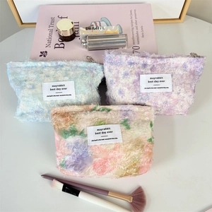Detailed view of three textured plush cosmetic bags in blue, lilac and pink floral patterns