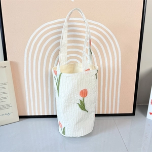 Detail der weißen Tulpenstickerei auf vertikalem Plissee-Stoff der runden Tasche