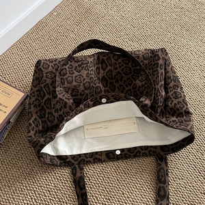Leopard print canvas tote bag with internal zip pocket and magnetic closure shown on mat