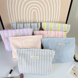 Detail of seersucker cosmetic bags with pleated stripes and a high-quality metal zipper