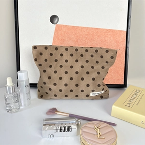 Detail of polka dot corduroy makeup bag with cosmetics on a white table background