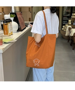 Détail d'un sac fourre-tout en toile orange avec motif de chiot blanc et texte