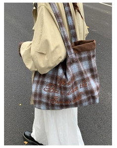 Detailed close-up of blue plaid wool tote bag with brown embroidery and corduroy lining