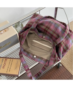 Detail view of plaid tote bag interior showing the zipper pocket and magnetic snap