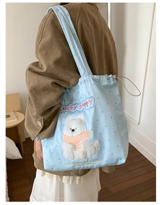 Detail view of cute 3D puppy embroidery and polka dots on light blue canvas tote bag