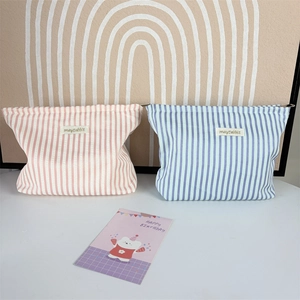 Detail of pink and blue striped fabric cosmetic bags with zip closure and woven brand tag