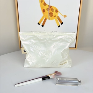 Detail of pearl white quilted makeup bag with elegant bow pattern and zip closure