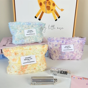 Detailed macro view of fuzzy floral cosmetic bags in blue, purple and yellow pastel tones