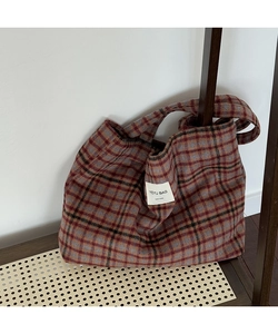Detailed close-up of a vintage plaid tote bag with handmade label in a home setting