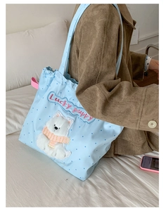 Detail of light blue polka dot tote bag featuring a plush puppy patch and embroidery