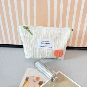 Detail der Tulpenstickerei und Faltenstruktur auf der cremefarbenen Kosmetiktasche