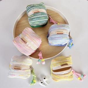 Detail of five colorful knit earbud cases with bead zippers on a wooden tray