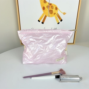 Detailed view of pink quilted makeup bag with bow pattern and metal zipper closure