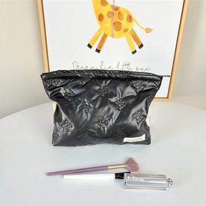 Detailed view of black quilted makeup bag with bow texture and zipper closure