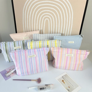 Close-up of textured striped makeup bags with metal zippers in various pastel colors