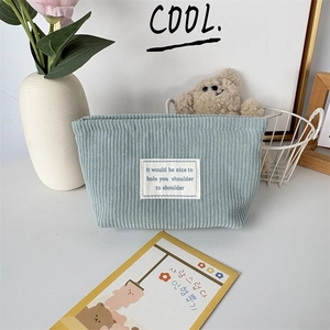 Detail of light blue corduroy makeup bag featuring a minimalist white fabric label patch