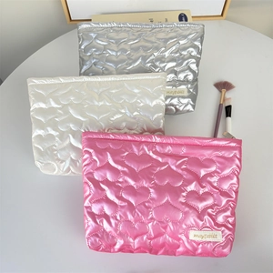 Glossy heart-quilted PU makeup bags in pink, white, and silver with a top zipper