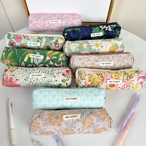 Estuches de lona con motivos florales y geométricos con etiqueta May Rabbit en mesa blanca