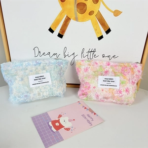 Detailed view of floral plush cosmetic bags with zipper closure and woven label
