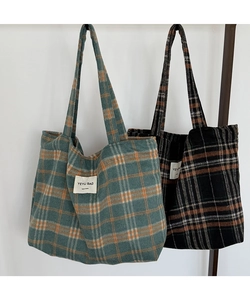 Close-up of retro plaid fabric textures and brand labels on large tote bags