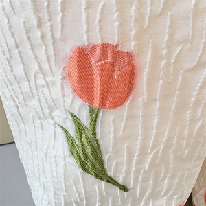 Detailaufnahme der Tulpenstickerei auf einer strukturierten Crepe-Schultertasche