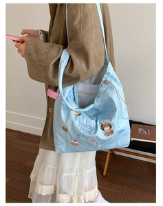 Detail view of light blue tote bag with cute cartoon embroidery and drawstring closure