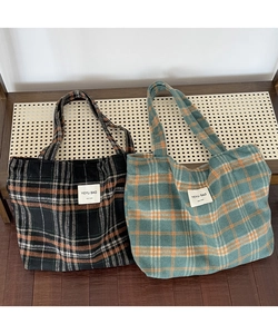 Detailed view of handmade plaid tote bags featuring orange lines and brand labels