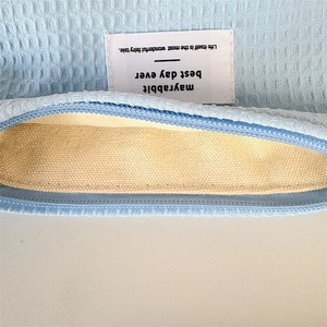 Detailed close-up of blue waffle fabric makeup bag featuring white brand label and zipper